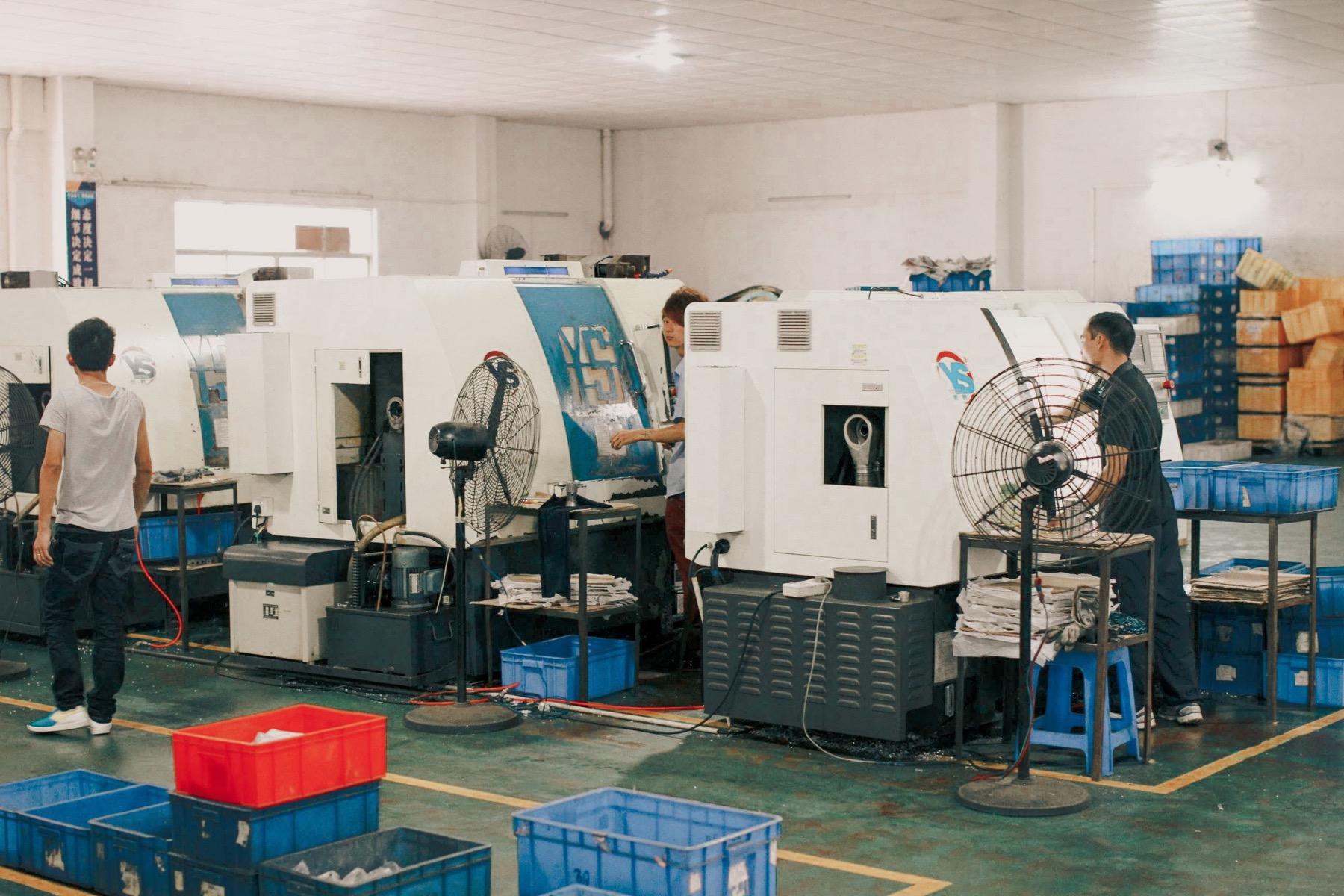 Workers operating machinery in an industrial factory setting.